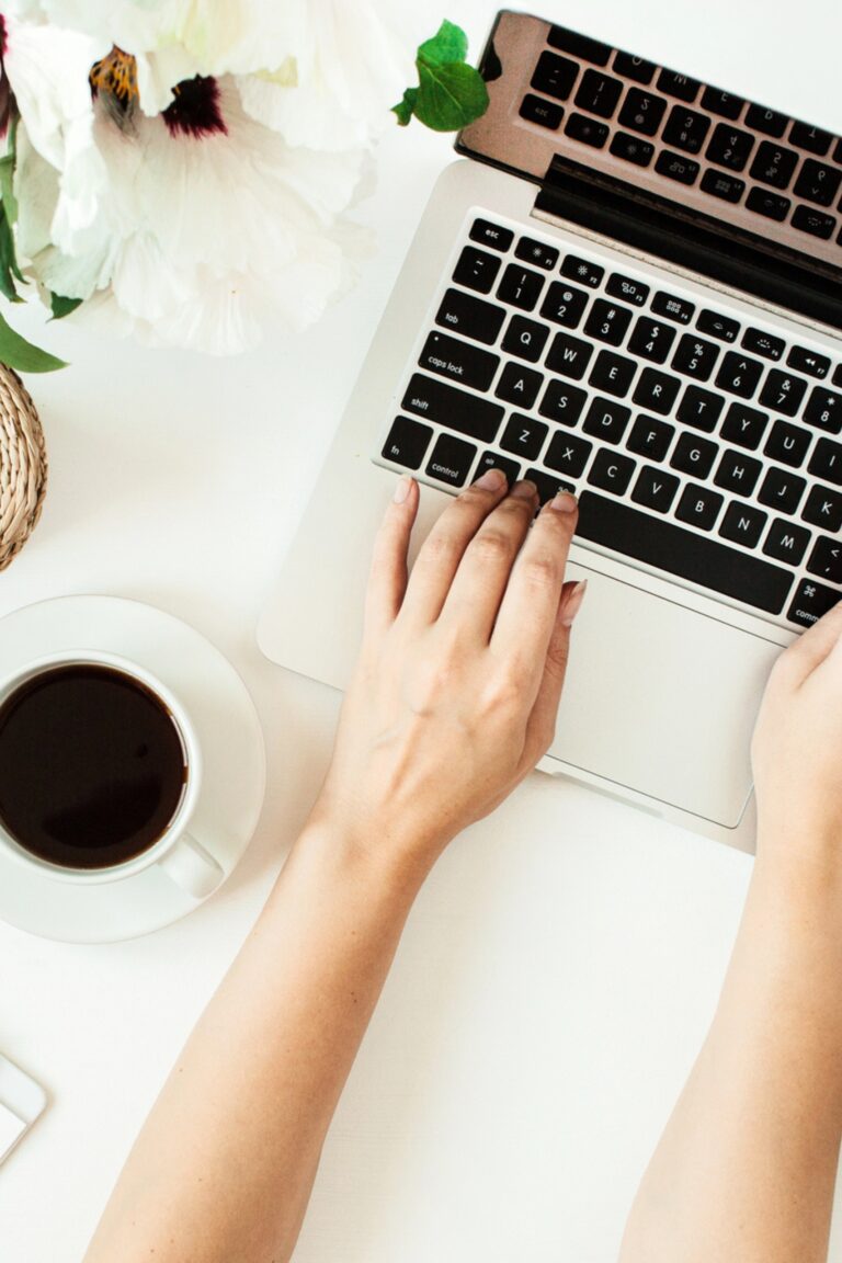 Hands on a laptop computer with a cup of coffee.