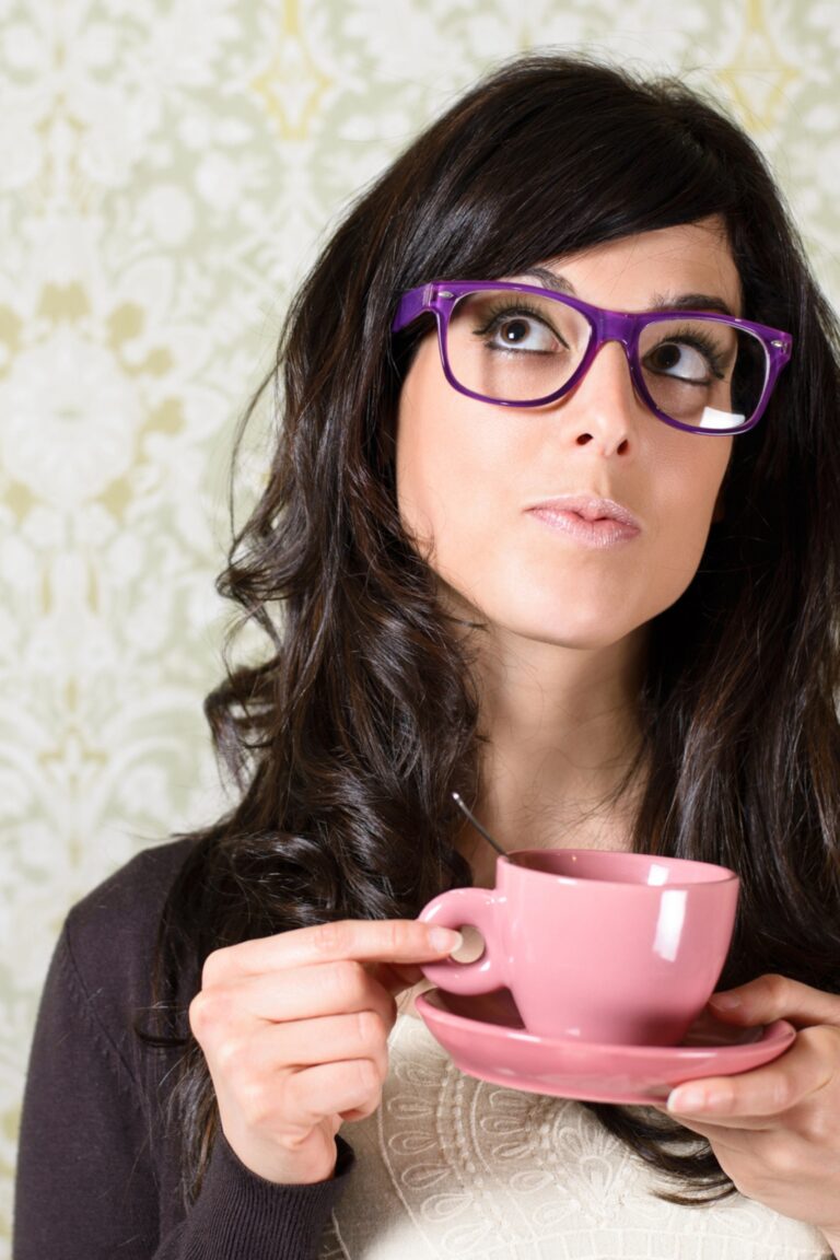 Brown headed woman with glasses holding a pink teacup.
