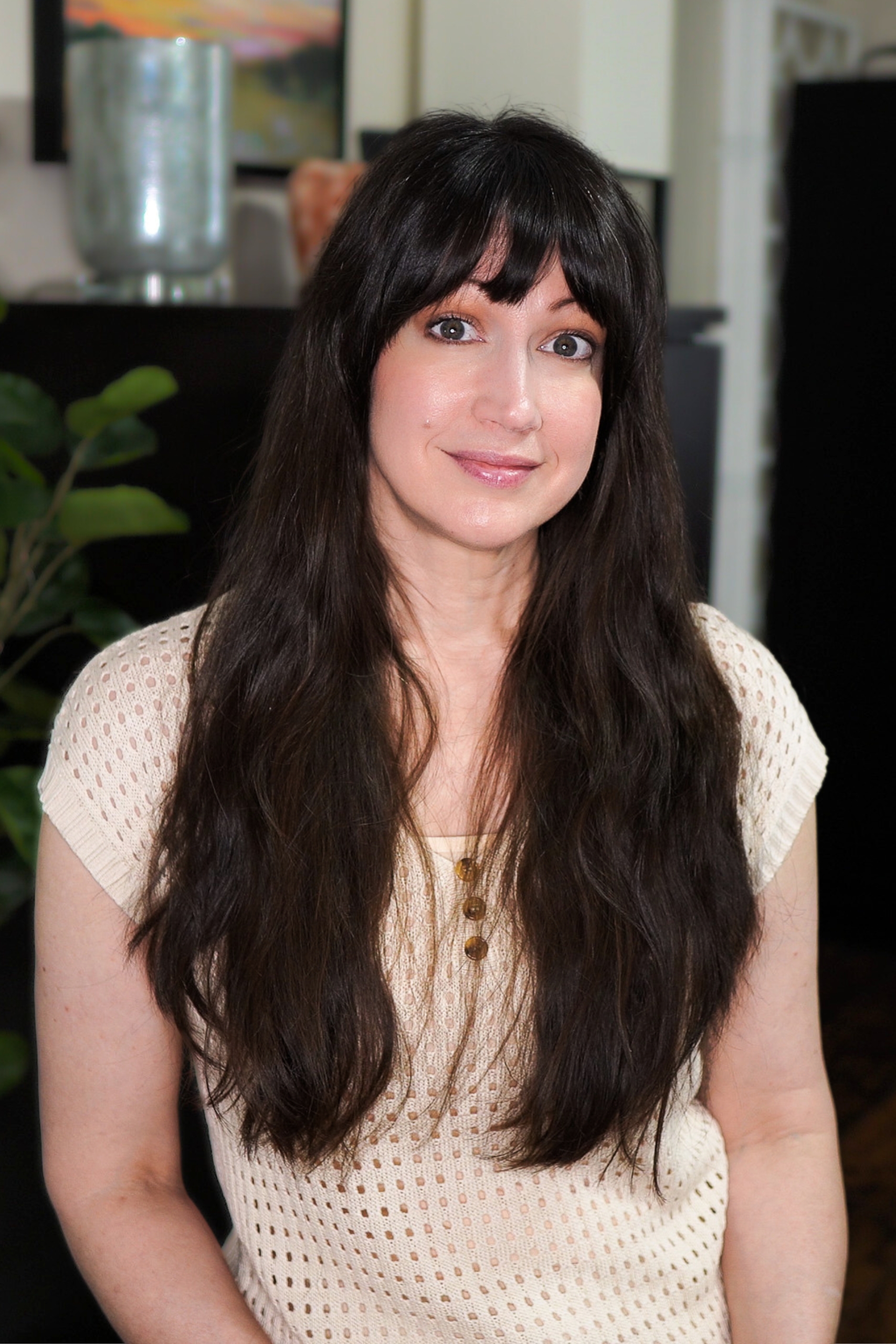 Image of woman with dark hair sitting in a chair with a pensive look.